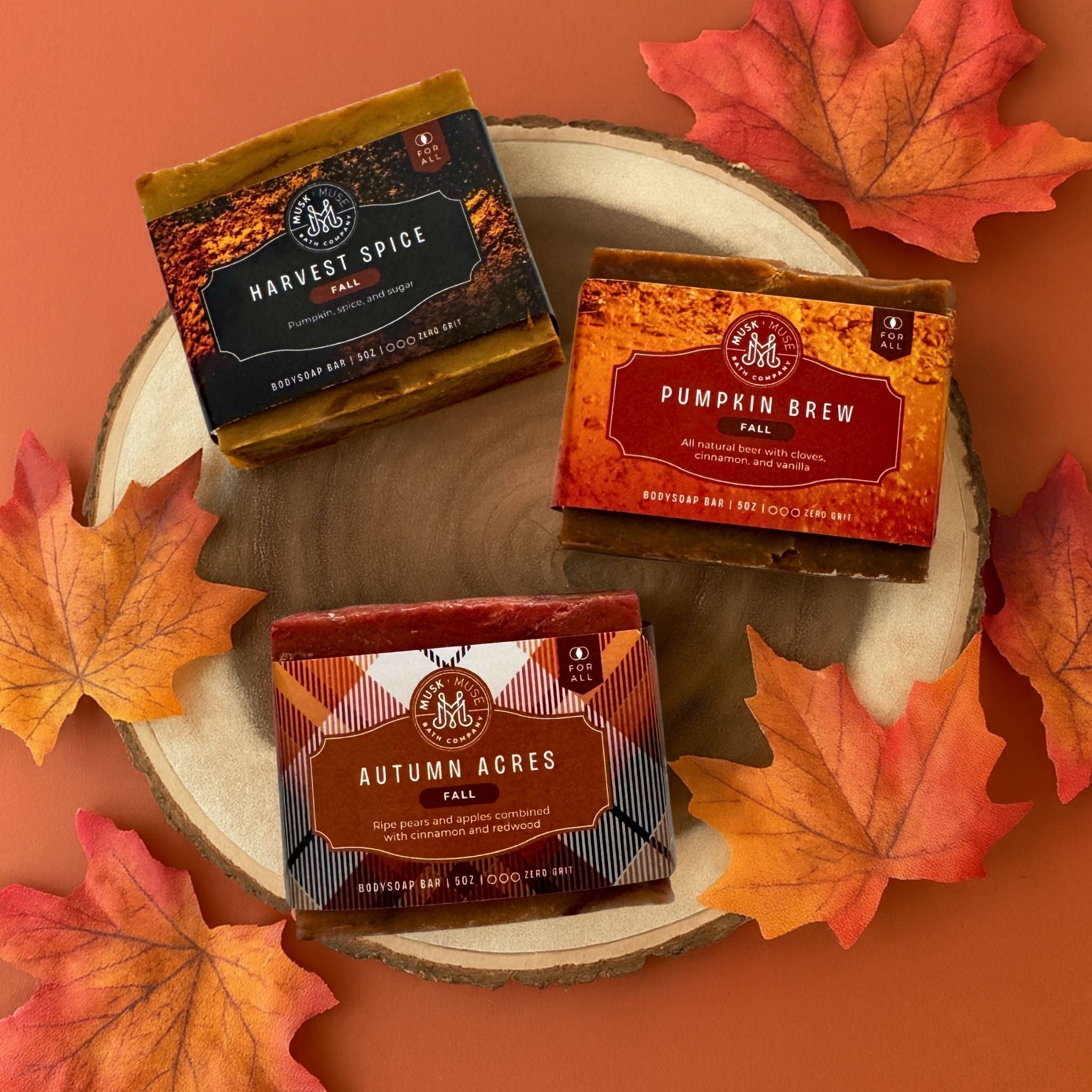Three fall scented bar soaps on a wood slice surrounded by fall leaves